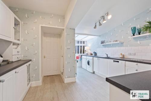 a kitchen with white cabinets and white appliances at Seagull Cottage in Hunstanton