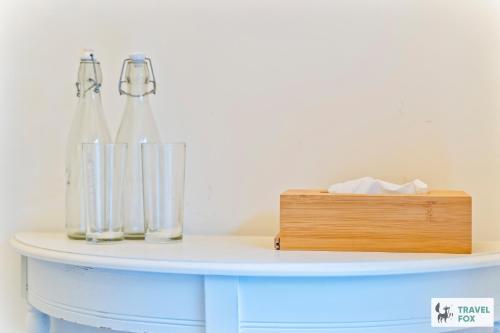 a white table with two glass bottles and a wooden box at Seagull Cottage in Hunstanton