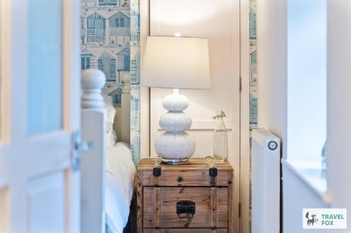 a lamp on a wooden table in a bedroom at Seagull Cottage in Hunstanton