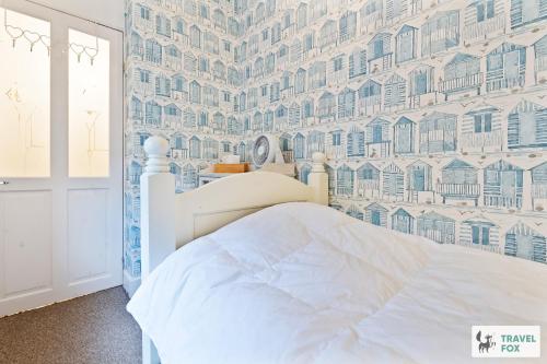a bedroom with a white bed and a wall of buildings at Seagull Cottage in Hunstanton