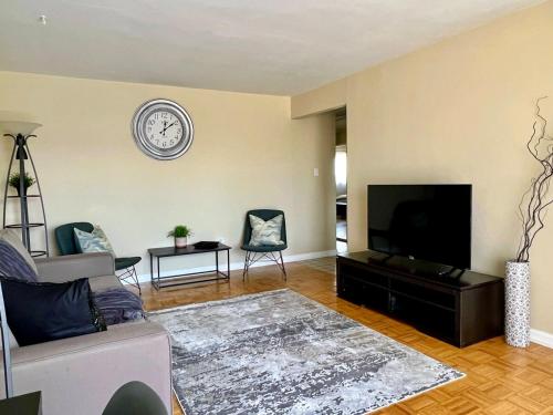 a living room with a couch and a clock on the wall at Bright 2 BR pet friendly, KING bed, WiFi,2 parking in Kitchener