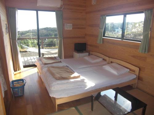 a bedroom with a bed in a room with windows at Minnsyuku Yakushimaya in Yakushima