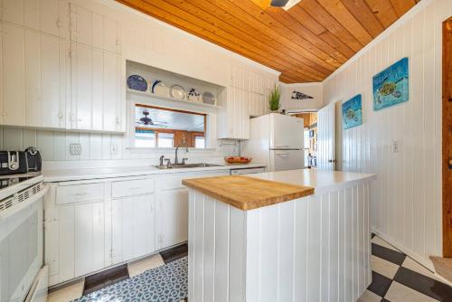 a kitchen with white cabinets and a wooden ceiling at Gypsea Rose in Southern Shores
