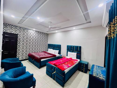 a bedroom with two beds and blue chairs at Millat Guest House G94 in Islamabad