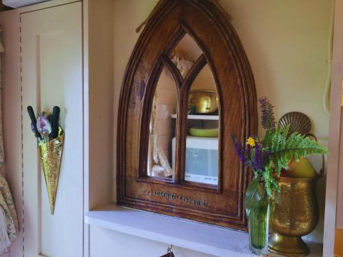 a wooden mirror on a shelf with a vase of flowers at The Gypsy Knot in Wells next the Sea