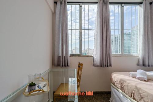 een slaapkamer met een bed, een tafel en ramen bij Suite no Centro do Rio com vista para a cidade in Rio de Janeiro