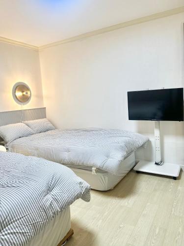 a bedroom with two beds and a flat screen tv at Konkuk Univ 2BR Cozy Apartment near Subway in Seoul