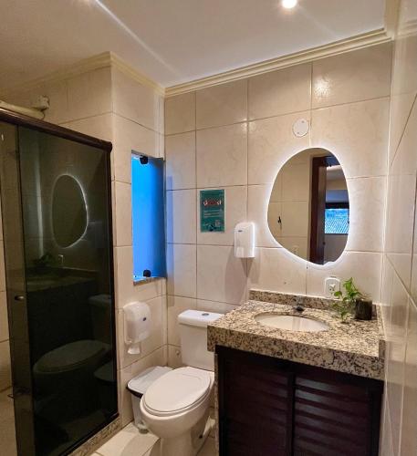 a bathroom with a toilet and a sink and a mirror at Chamos Hostel Cultural in Arraial do Cabo