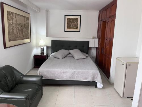 a bedroom with a bed and a leather couch at HOTEL COSTA DEL SOL FUSAGASUGa in Fusagasuga