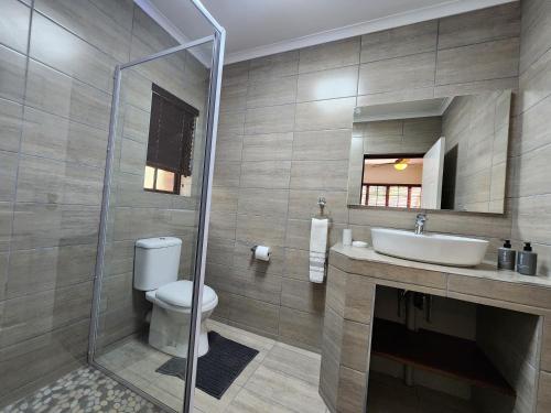 a bathroom with a toilet and a sink and a shower at Kensington Lodge Golf Estate Villa - 17 Pinehurst Drive in White River