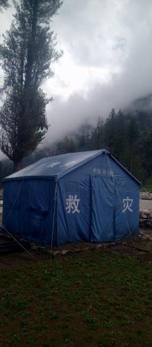 a blue tent in a field with writing on it at Baba Jani Kumrat in Tāl