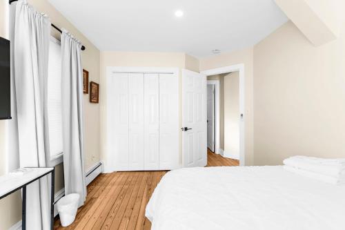 a white bedroom with a bed and a window at The Seafarers Stay A Nautically Themed 3BR Flat in Stonington Borough in Stonington