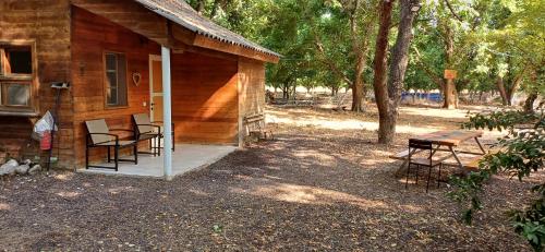a wooden cabin with chairs and a bench on a porch at חווה של דני in Bet Hillel