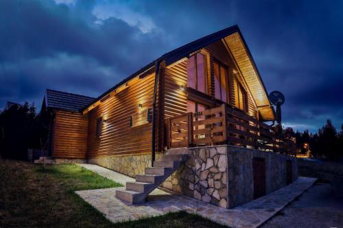 a wooden house with a stone wall at Planinska kuća Lastino gnezdo in Bajina Bašta