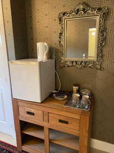a refrigerator on top of a wooden dresser with a mirror at Doune Duck Ponds Accommodation in Doune