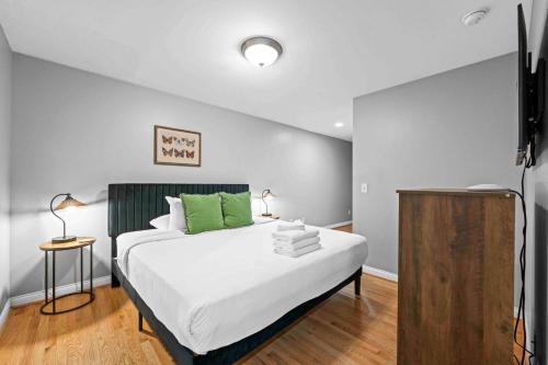 a bedroom with a bed with white sheets and green pillows at The City Staycation Condo - Downtown Cincy Views in Covington