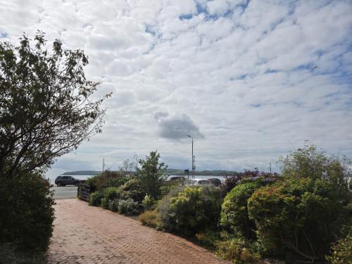 a brick road with bushes and a cloudy sky at The Old Rectory in Largs