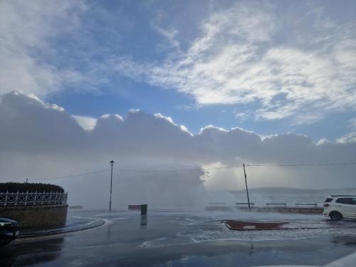 a car is parked in a parking lot with a cloudy sky at The Old Rectory in Largs