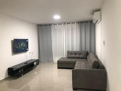 a living room with a couch and a flat screen tv at Isramax 3BR apartment near the sea. in Bat Yam