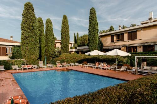 a swimming pool with chairs and umbrellas and trees at Residence Poggio Golf Chianti Firenze in Impruneta