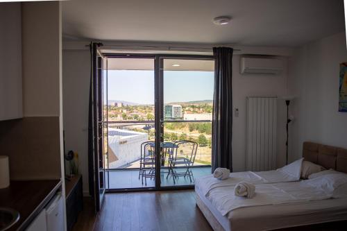 a bedroom with a bed and a view of a balcony at Planet Residence Royal Studio & SPA in Niš