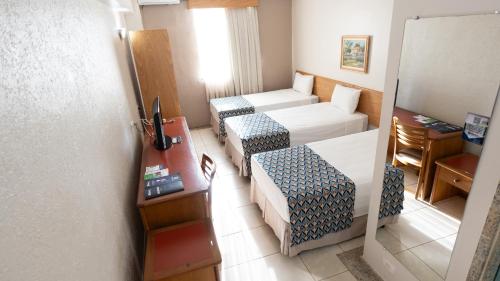 a hotel room with two beds and a door at Hotel Dan Inn Franca & Convenções By Nacional Inn in Franca