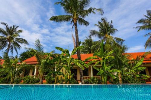 a house with palm trees and a swimming pool at Hula Hula Seafront Phu Quoc in Phu Quoc