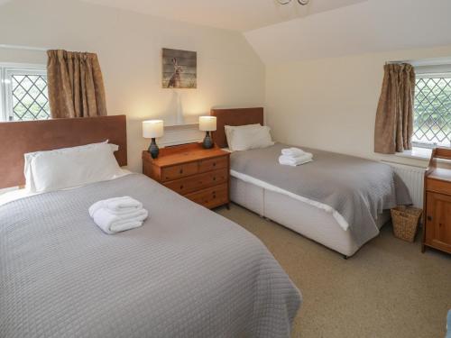 a bedroom with two beds and two lamps and windows at Hillside Cottage in Monmouth