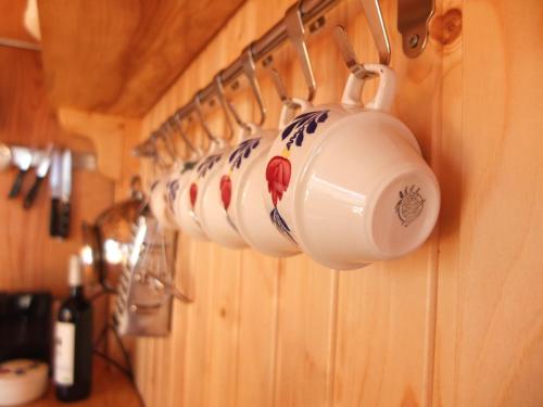 a row of coffee cups hanging on a wall at Shepherd's hut De Skoeboet in Sint Maartensbrug