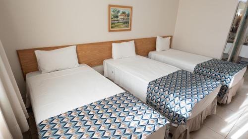 three beds in a row in a room at Hotel Dan Inn Franca & Convenções By Nacional Inn in Franca