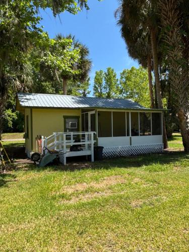a small yellow cottage with a porch and trees at Harmons Landing in Hawthorne