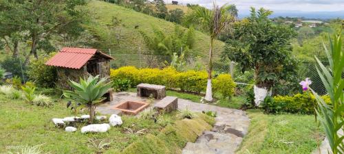 a garden with a small house and some animals at Alojamiento EL GITANO in Filandia