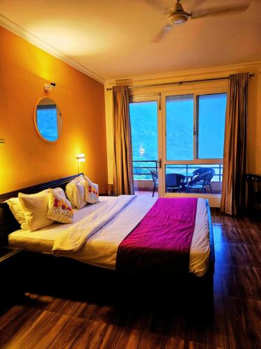 a bedroom with a large bed with a large window at Aloha Apartments by blissful Ganges in Rishīkesh