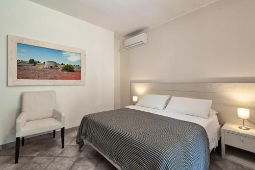 a white bedroom with a bed and a chair at Olive Garden House in Borgagne
