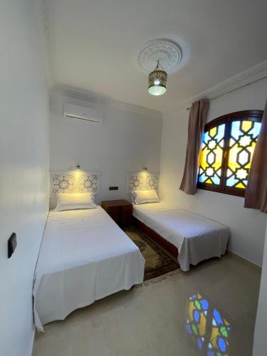 two beds in a room with a window and two bedsvisor at Diaft'na in Marrakech