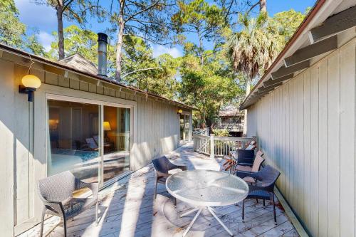 eine Terrasse mit einem Tisch und Stühlen neben einem Gebäude in der Unterkunft 1038 Sparrow Pond in Kiawah Island