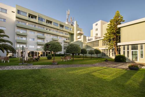 a courtyard of a building with chairs and trees at Axis Ofir Beach Resort Hotel in Esposende