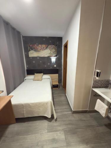 a bedroom with a white bed in a room at Hostal Falfes in Madrid
