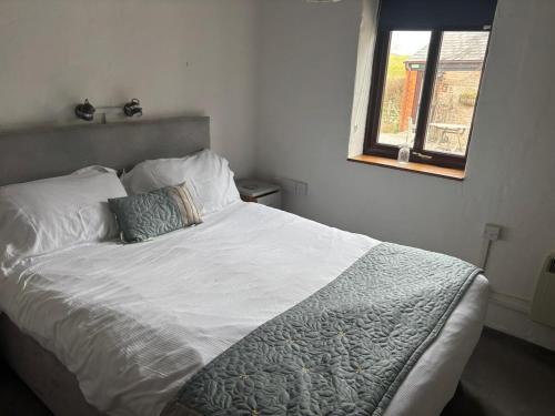 ein weißes Bett in einem Schlafzimmer mit einem Fenster in der Unterkunft lovely Apple Cottage A peach in Bridport