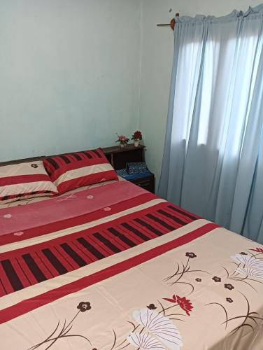 a bedroom with a bed with a red and white blanket at Familia Cabrera Rojas in Nueva Alborada