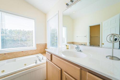 a bathroom with a tub and a sink and a mirror at King BEEch in Southern Shores