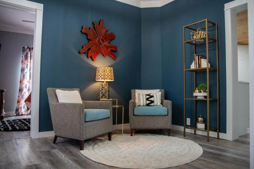 a living room with two chairs and a clock on the wall at Priceless on Price St Walk to downtown! in Mount Airy