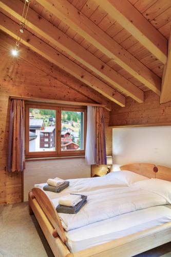two beds in a bedroom with a wooden ceiling at Dominic A in Saas-Fee