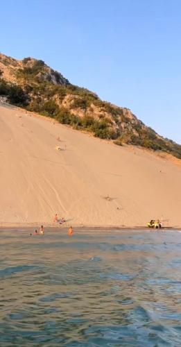 a sandy beach with people swimming in the water at Deluxe Apartments Shengjin in Shëngjin
