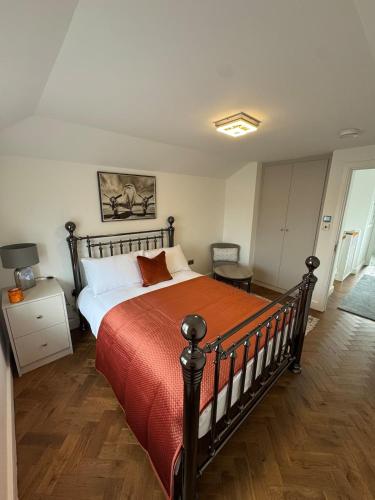 a bedroom with a large bed with a red blanket at Siennas Modern 1 bed room apartment with ensuite in Kidlington