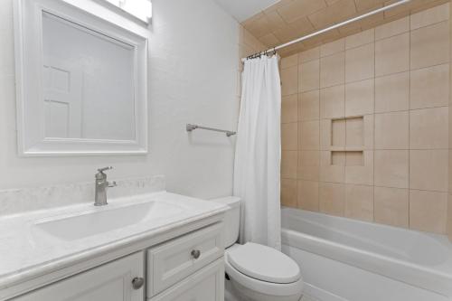 a white bathroom with a sink and a toilet at Shades of Summer by AvantStay Gazebo Dock View in Cornelius