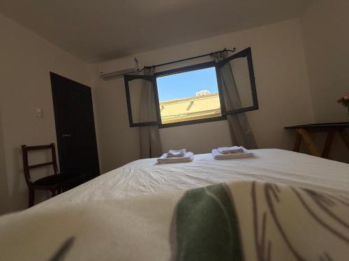 a bedroom with a bed and a window with towels on it at Clivias Hostel in Salta