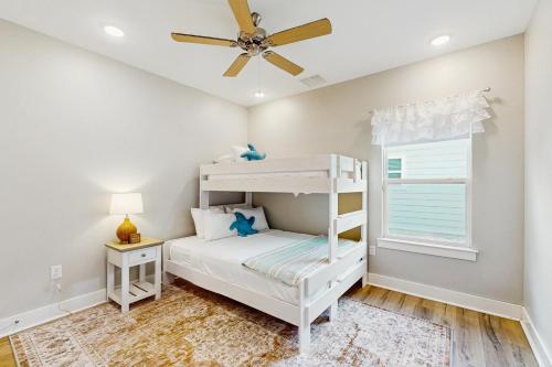 een slaapkamer met een stapelbed en een plafondventilator bij Seaglass Cottage in Rockport