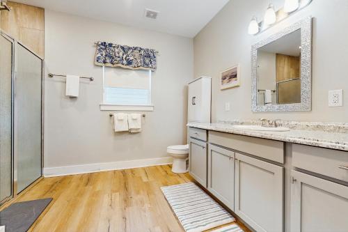 een badkamer met een wastafel, een toilet en een spiegel bij Seaglass Cottage in Rockport