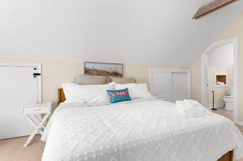 a white bedroom with a large white bed and a bathroom at The Seafarers Stay A Nautically Themed 3BR Flat in Stonington Borough in Stonington